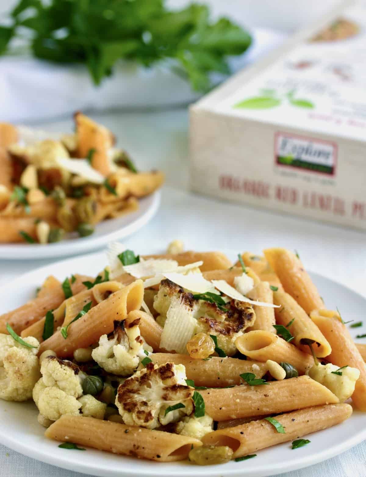 plates of penne pasta with cauliflower, herbs and product package
