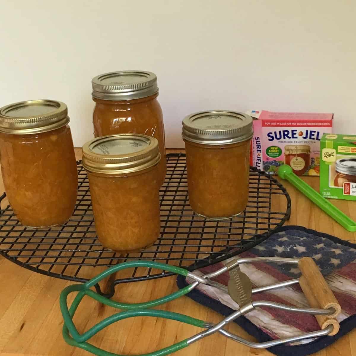 jars of the best peach jam with canning supplies